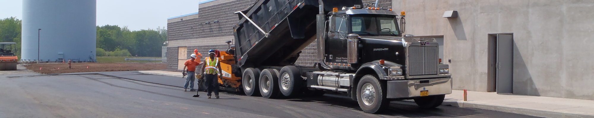 workers with a truck tipped dumping pavement