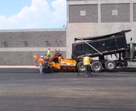 workers watching over truck dumbing pavement