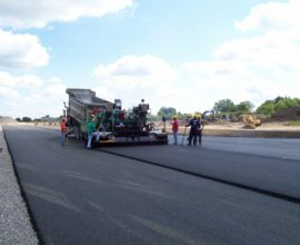 workers smoothing pavement on a long road