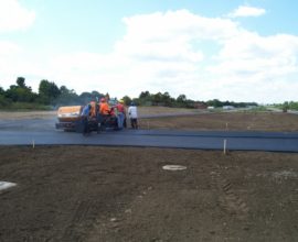 workers carrying the smoothing machine around a road corner