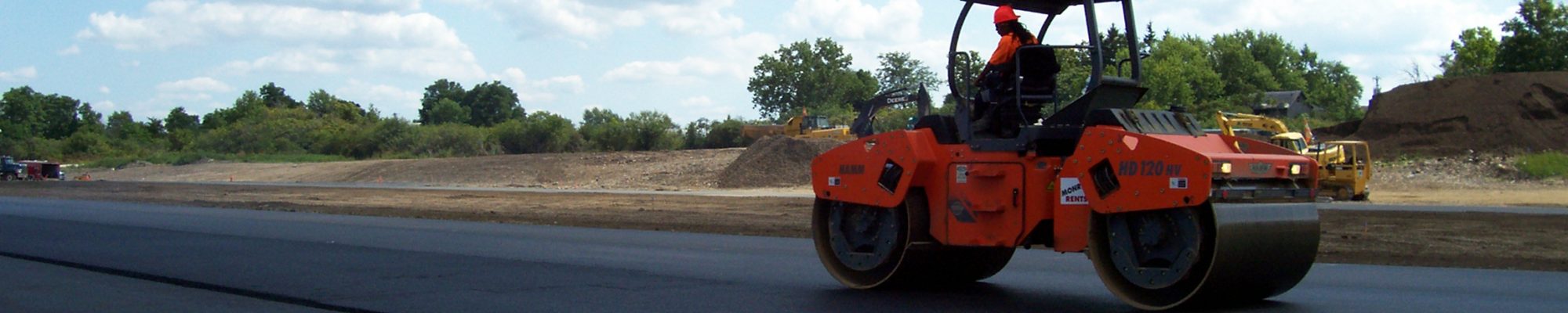 single man in a machine smoothing new fresh pavement