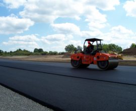 single man in a machine smoothing new fresh pavement