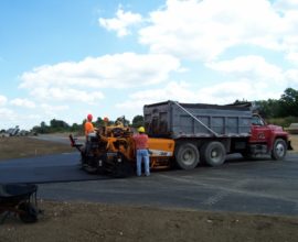 two workers smoothing pavement and using a truck