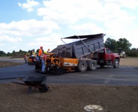 two workers helping to lift dirt form truck