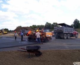 large group of people placing pavement onto the old road