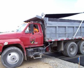 man in orange shirt driving red truck