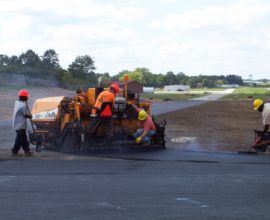 workers hunched over machine smoothing the pavement